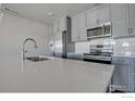 Updated kitchen features stainless steel appliances, gray cabinets, white subway tile backsplash, and a modern faucet at 235 High Point Dr # 103, Longmont, CO 80504