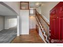 Bright foyer with hardwood floors, staircase, and a view into the carpeted living room at 355 Sprucewood Ct, Lafayette, CO 80026