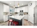 Bright kitchen features white cabinets, stainless steel appliances, quartz counters, and an island with seating at 364 Shawnee Ln, Superior, CO 80027
