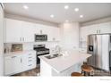 Modern kitchen with white cabinets, stainless steel appliances, quartz countertops, and an island with seating at 5805 Red Barn Ave, Mead, CO 80542