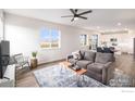Cozy living room with a gray sofa, stylish rug, and a view into the adjacent kitchen at 5805 Red Barn Ave, Mead, CO 80542