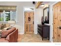 Stylish entryway with hardwood floors, wooden door, modern console table, and decorative mirror at 9445 Lykins Pl, Boulder, CO 80301