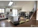 Open living area featuring a kitchen island, dining table, modern fireplace, and staircase at 1701 Sumner St, Longmont, CO 80501