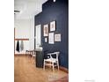 Entryway featuring wood floors, a dark accent wall with artwork, and a modern table with chair at 2351 Federal Blvd # 102, Denver, CO 80236