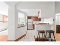 Open kitchen view with stainless steel appliances, breakfast bar, and tiled flooring at 2351 Federal Blvd # 102, Denver, CO 80236