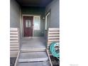 Inviting front porch with a classic red door, light-colored siding, and gray steps leading to the entryway at 2569 Stonewall Ln, Lafayette, CO 80026