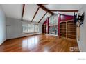 Spacious living room with hardwood floors, stone fireplace, beamed ceiling, and built-in bookshelves at 600 Ramona Ct, Berthoud, CO 80513