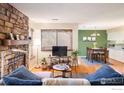 Cozy living room with stone fireplace, wood floors, and an open view to the dining area at 6251 Willow Ln, Boulder, CO 80301