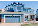 Attractive two-story blue home featuring a stone facade, attached garage and a well-manicured lawn at 10081 Blackbird Cir, Highlands Ranch, CO 80130