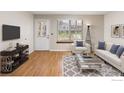Comfortable living room with hardwood floors, white sofa, armchair, and modern TV console at 104 Pheasant Run, Louisville, CO 80027