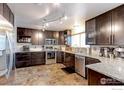 Modern kitchen with granite countertops, stainless steel appliances, and beautiful brown cabinets at 10679 Union Way, Broomfield, CO 80021