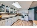 Well-lit kitchen with white cabinets, dark countertops, and wood-look flooring at 1222 Atwood St, Longmont, CO 80501