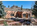 Exterior view of home with patio and seating area overlooking the wooded lot at 136 Old Post Office Rd, Boulder, CO 80302