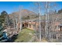 View of the exterior of the home showcasing mature trees and a sloping lot at 136 Old Post Office Rd, Boulder, CO 80302