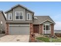 Two-story home featuring gray siding, brick accents, a two-car garage, and front yard landscaping at 16645 W 2Nd Ave, Golden, CO 80401