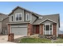 Two-story home featuring gray siding, brick accents, a two-car garage, and front yard landscaping at 16645 W 2Nd Ave, Golden, CO 80401