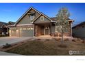Inviting home exterior with stone accents, a two-car garage, and cozy seating on the porch at 2882 Heron Lakes Pkwy, Berthoud, CO 80513