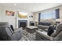 Cozy living room featuring a fireplace, comfortable gray seating, and bright natural light from large windows at 450 Pikes View Dr, Erie, CO 80516