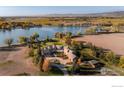 Stunning aerial view of a lakefront estate featuring lush landscaping, mature trees, and mountain views at 9402 Crystal Ln, Longmont, CO 80503