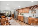 Open kitchen with stainless steel appliances, wood cabinets, and a dining nook adjacent to the living area at 1226 Atwood St, Longmont, CO 80501