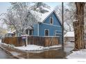 Charming two-story blue home with mature trees and a wooden fence, creating a picturesque snowy scene at 1605 17Th St, Boulder, CO 80302