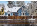 Charming two-story blue home with mature trees and a wooden fence, creating a picturesque snowy scene at 1605 17Th St, Boulder, CO 80302