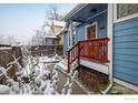 Charming blue home featuring a covered front entrance with a red-railed stairway and snow-covered landscaping at 1605 17Th St, Boulder, CO 80302