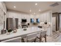 Modern kitchen featuring a center island with seating, stainless steel appliances, white cabinets, and stylish backsplash at 900 W 128Th Pl, Westminster, CO 80234