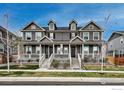 View of townhomes with covered front porches, neutral exteriors, and professional landscaping at 17614 Cherokee St, Broomfield, CO 80023