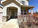Covered front porch with stone accents and manicured landscaping at 2432 Tyrrhenian Dr, Longmont, CO 80504