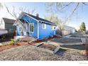 Blue bungalow home exterior with side yard raised garden beds and gravel, set under a sunny sky at 245 2Nd St, Fort Lupton, CO 80621