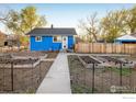 Quaint blue home with a well-kept garden and a charming walkway leading to the front door at 245 2Nd St, Fort Lupton, CO 80621