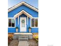 Inviting blue home with white door, a lovely wreath, and potted plants framing the entrance at 245 2Nd St, Fort Lupton, CO 80621