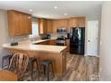 Well-lit kitchen with oak cabinets, stainless steel appliances, a breakfast bar, and wood-look flooring at 318 E Iowa Ave, Berthoud, CO 80513