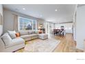 Open-concept living area with a large sectional sofa, wood floors, and seamless flow to the kitchen at 3196 Park St, Mead, CO 80542