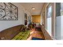 Inviting sunroom featuring wood floors, cozy seating, and bright natural light streaming through numerous windows at 42 Marshall Pl, Longmont, CO 80504