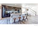 Open-concept kitchen featuring a large island with seating, stainless steel appliances, and dark wood cabinetry at 4783 S Wenatchee Cir, Aurora, CO 80015
