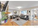 Bright living room featuring a stone fireplace, hardwood floors, a large window, and comfortable leather seating at 6221 Willow Ln, Boulder, CO 80301