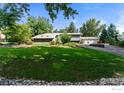 Expansive green lawn leading up to a modern gray home with a metal roof and a multi-car garage at 7451 Rozena Dr, Longmont, CO 80503
