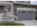 Close-up of a home's gray garage door, stone exterior, and entryway with steps leading up to the front porch at 1031 Turnberry Cir, Louisville, CO 80027