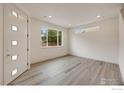 Bright living room with modern gray wood floors, white walls, and natural light from the large windows at 1043 Spartan Ave, Berthoud, CO 80513