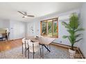 Airy dining area with a ceiling fan, a modern wood table, white chairs and a bay window offering natural light at 11382 Flatiron Dr, Lafayette, CO 80026