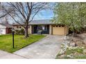Charming single-story home with a brick and navy blue facade, a driveway, and mature trees at 1527 Sherri Mar St, Longmont, CO 80501