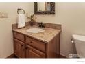 Stylish bathroom with a granite countertop, wooden vanity, and a decorative mirror at 1715 Wales Dr, Berthoud, CO 80513