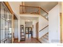 Spacious foyer with hardwood floors, soaring ceilings, and open staircase leading to the upper level at 1715 Wales Dr, Berthoud, CO 80513