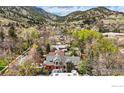 Breathtaking aerial view showcases the serene neighborhood nestled among green mountains and mature trees at 563 Arapahoe Ave, Boulder, CO 80302