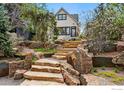 Charming home with stone stairs leading to the entrance, surrounded by lush landscaping and trees at 563 Arapahoe Ave, Boulder, CO 80302