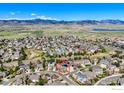 Aerial view of neighborhood with homes, green spaces, and a distant lake at 6263 Torrey Ln, Arvada, CO 80403