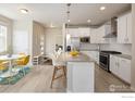 Well-lit kitchen featuring white cabinets, stainless steel appliances, and a granite-topped island with bar seating at 655 Stonebridge Dr, Longmont, CO 80503