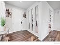 Bright entryway with modern wood-look floors, decorative paneling, and a view into adjacent living spaces at 6935 E 133Rd Ave, Thornton, CO 80602
